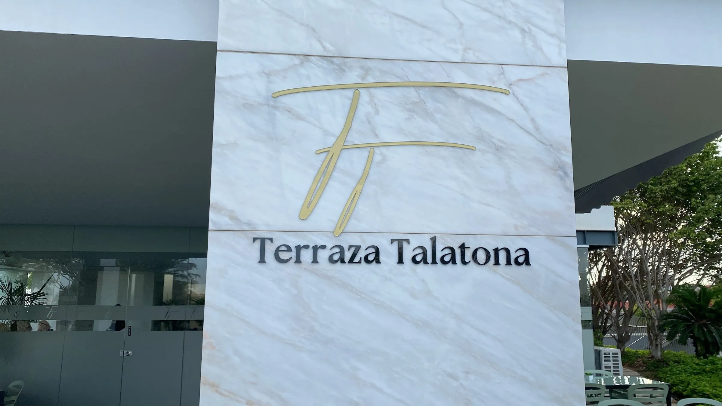 Parede de mármore com o monograma dourado e o nome Terraza Talatona