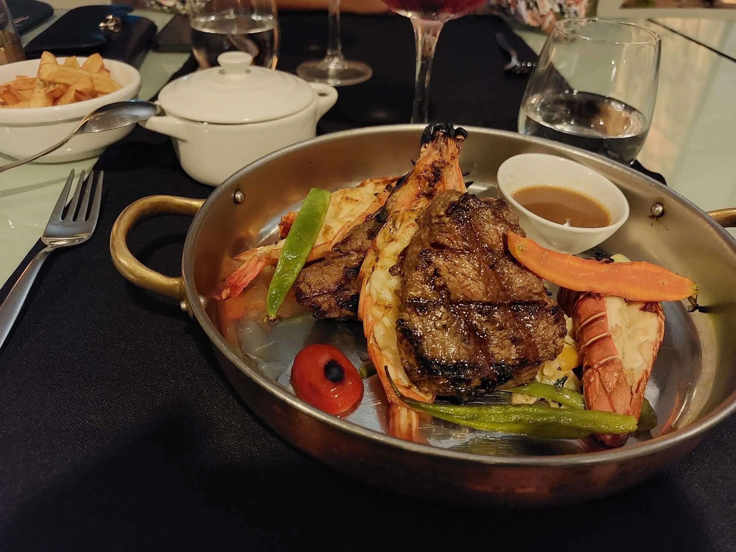 Surf and turf: bife grelhado com lagostins e legumes num tacho de cobre